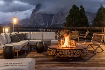 a fire pit on a deck with a couch and chairs at Paradiso Pure Living Vegan Hotel in Alpe di Siusi