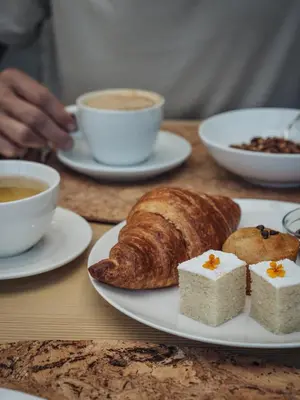 a table with cups of coffee and a plate of bread at Paradiso Pure Living Vegan Hotel in Alpe di Siusi
