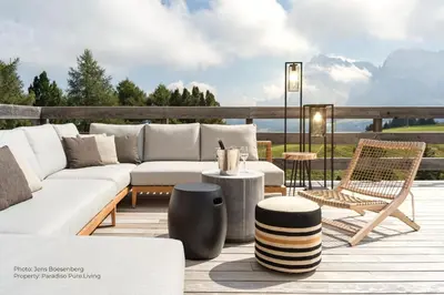 a patio with a couch and chairs on a deck at Paradiso Pure Living Vegan Hotel in Alpe di Siusi