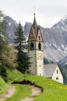 a church with a clock tower on the side of a hill at Apartments Ruac in La Valle