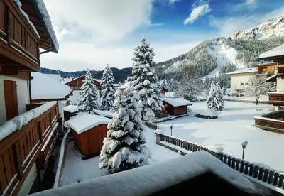 a snow covered christmas tree in front of a house at Garni Gabrieli in Corvara in Badia