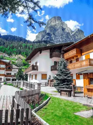 a building with a tree in front of a mountain at Garni Gabrieli in Corvara in Badia