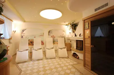 a group of chairs in a room with a fireplace at Villa Perla in Selva di Val Gardena