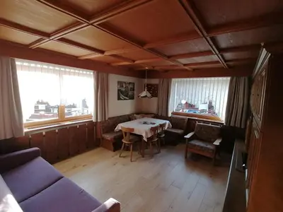 a living room with a table and chairs and windows at Villa Perla in Selva di Val Gardena