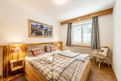 a bedroom with a large bed and a window at Laurino Apartment in Campitello di Fassa