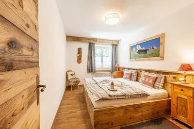 a bedroom with a bed and a wooden wall at Laurino Apartment in Campitello di Fassa