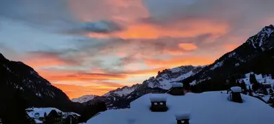 a sunset in the mountains with snow covered mountains at Laurino Apartment in Campitello di Fassa