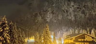 a ski lodge in front of a mountain at night at Laurino Apartment in Campitello di Fassa
