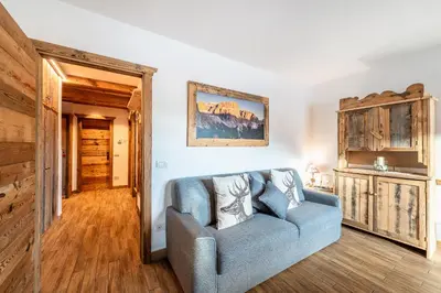 a living room with a blue couch and wooden floors at Laurino Apartment in Campitello di Fassa