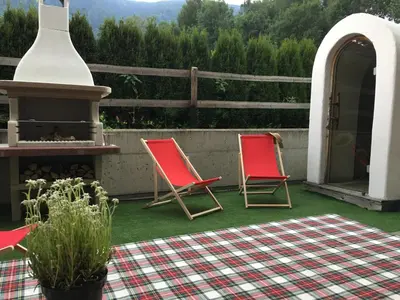 two red chairs on a patio with a fireplace at Apartment Plan Corones in Brunico