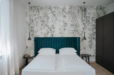 a bedroom with a large bed with a green headboard at Windsor Merano Hotel & Suites in Merano