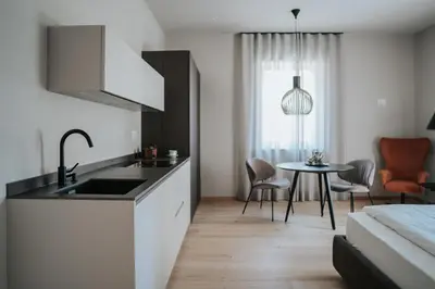a kitchen with a sink and a table at Windsor Merano Hotel & Suites in Merano