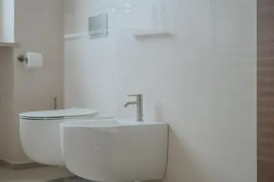 a white bathroom with a sink and a toilet at Windsor Merano Hotel & Suites in Merano