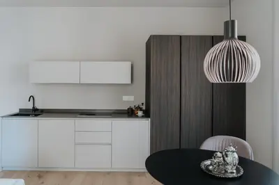 a kitchen with a table and a pendant light at Windsor Merano Hotel & Suites in Merano