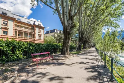 a red bench on a sidewalk next to a building at Windsor Merano Hotel & Suites in Merano
