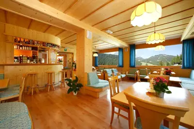 a restaurant with tables and chairs and a bar at Hotel Meisules in Selva di Val Gardena