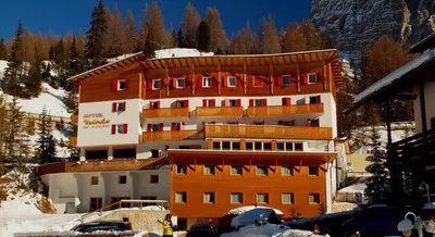 a large building with red windows in the snow at Hotel Meisules in Selva di Val Gardena