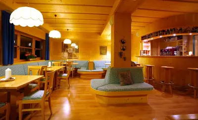 a restaurant with tables and chairs and a bar at Hotel Meisules in Selva di Val Gardena
