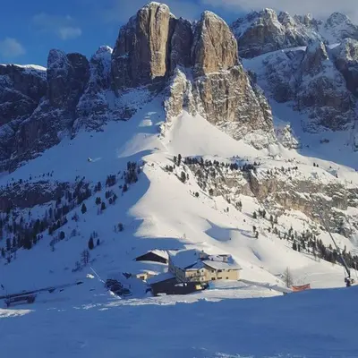 a building on a snowy mountain with people in the snow at Hotel Cir in Selva di Val Gardena