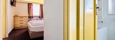 a small bedroom with a bed and a bath tub at Hotel Cir in Selva di Val Gardena