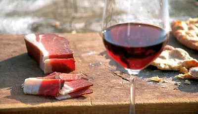 a glass of red wine next to a piece of meat at Hotel Cir in Selva di Val Gardena