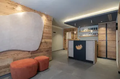 a lobby with a bench and a chair and a counter at Hotel Alpi in Campitello di Fassa