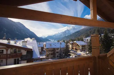 a view from a balcony of a town with snow covered mountains at Hotel Alpi in Campitello di Fassa