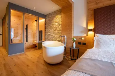 a bedroom with a bed and a bath tub in it at Hotel Alpi in Campitello di Fassa