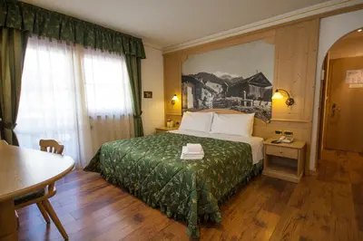 a hotel room with a bed and a table at Hotel Alpi in Campitello di Fassa
