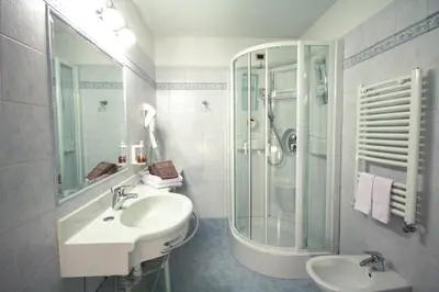 a white bathroom with a sink and a shower at Hotel Alpi in Campitello di Fassa