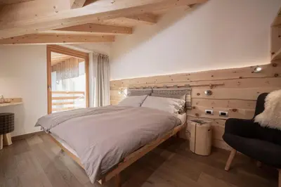 a large bed in a room with wooden walls at Agriturismo Soreie - Farmstay in Vigo di Fassa
