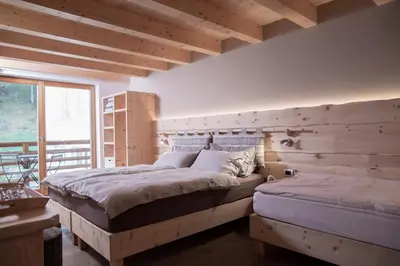 a bedroom with two bunk beds with white sheets at Agriturismo Soreie - Farmstay in Vigo di Fassa