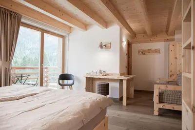 a bedroom with a bed and a large window at Agriturismo Soreie - Farmstay in Vigo di Fassa