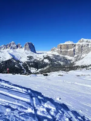 a snow covered slope with mountains in the background at Il Giornalgaio in Canazei