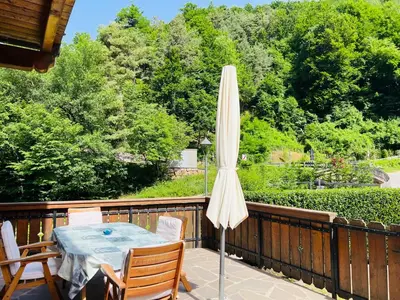 a patio with a table and an umbrella on a deck at Apartments Bernard in Aldino