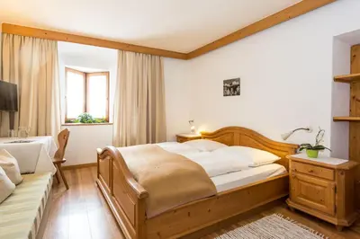 a bedroom with a wooden bed and a desk at Garni Zatzerhof in Castelrotto