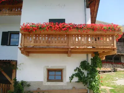 a balcony with red flowers on a building at Garni Zatzerhof in Castelrotto