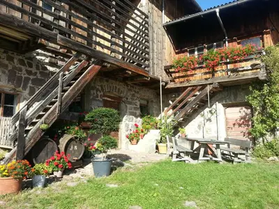 a house with a table and chairs and flowers at Garni Zatzerhof in Castelrotto
