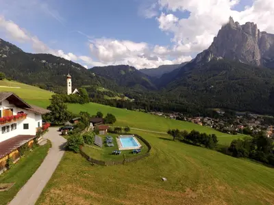 a house with a swimming pool in a field with mountains at Garni Zatzerhof in Castelrotto