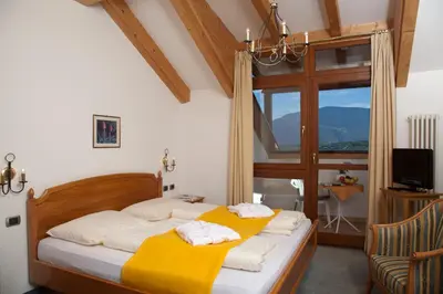 a bedroom with a bed with a yellow blanket at Hotel Lambrechtshof in Appiano sulla Strada del Vino