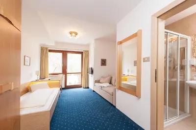 a hotel room with a couch and a bathroom at Hotel Lambrechtshof in Appiano sulla Strada del Vino