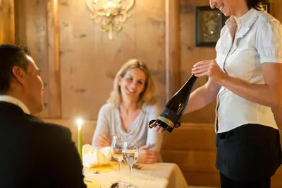 a woman pouring a glass of wine in a table at Hotel Lambrechtshof in Appiano sulla Strada del Vino