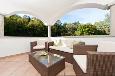 a patio with wicker furniture and a glass table at Hotel Lambrechtshof in Appiano sulla Strada del Vino