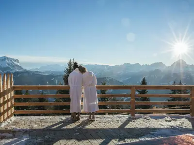 two people standing on a fence looking at the mountains at Rifugio Graziani Hütte in San Vigilio Di Marebbe