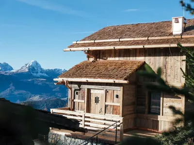 an old wooden house with a mountain in the background at Rifugio Graziani Hütte in San Vigilio Di Marebbe