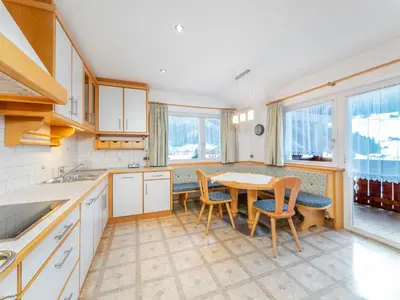 a kitchen with a table and chairs and windows at Apartment Plan de Socrep in Santa Cristina in Val Gardena