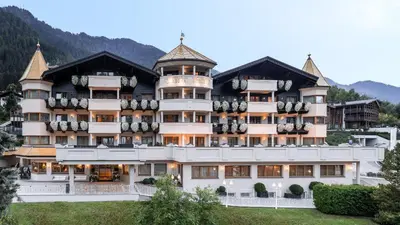 a hotel in the mountains with mountains in the background at Gardena Grödnerhof - Hotel & Spa in Ortisei