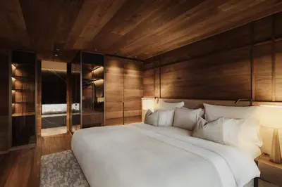 a bedroom with a large white bed and wooden walls at Gardena Grödnerhof - Hotel & Spa in Ortisei