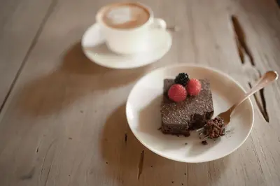 a piece of chocolate cake on a plate with a cup of coffee at Hotel Pollinger in Merano