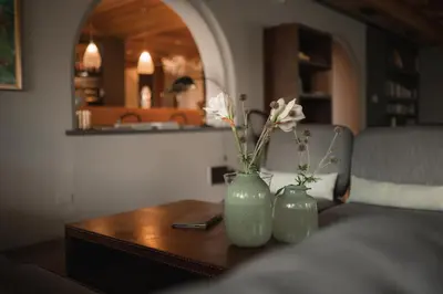 two green vases with flowers on a wooden table at Hotel Pollinger in Merano